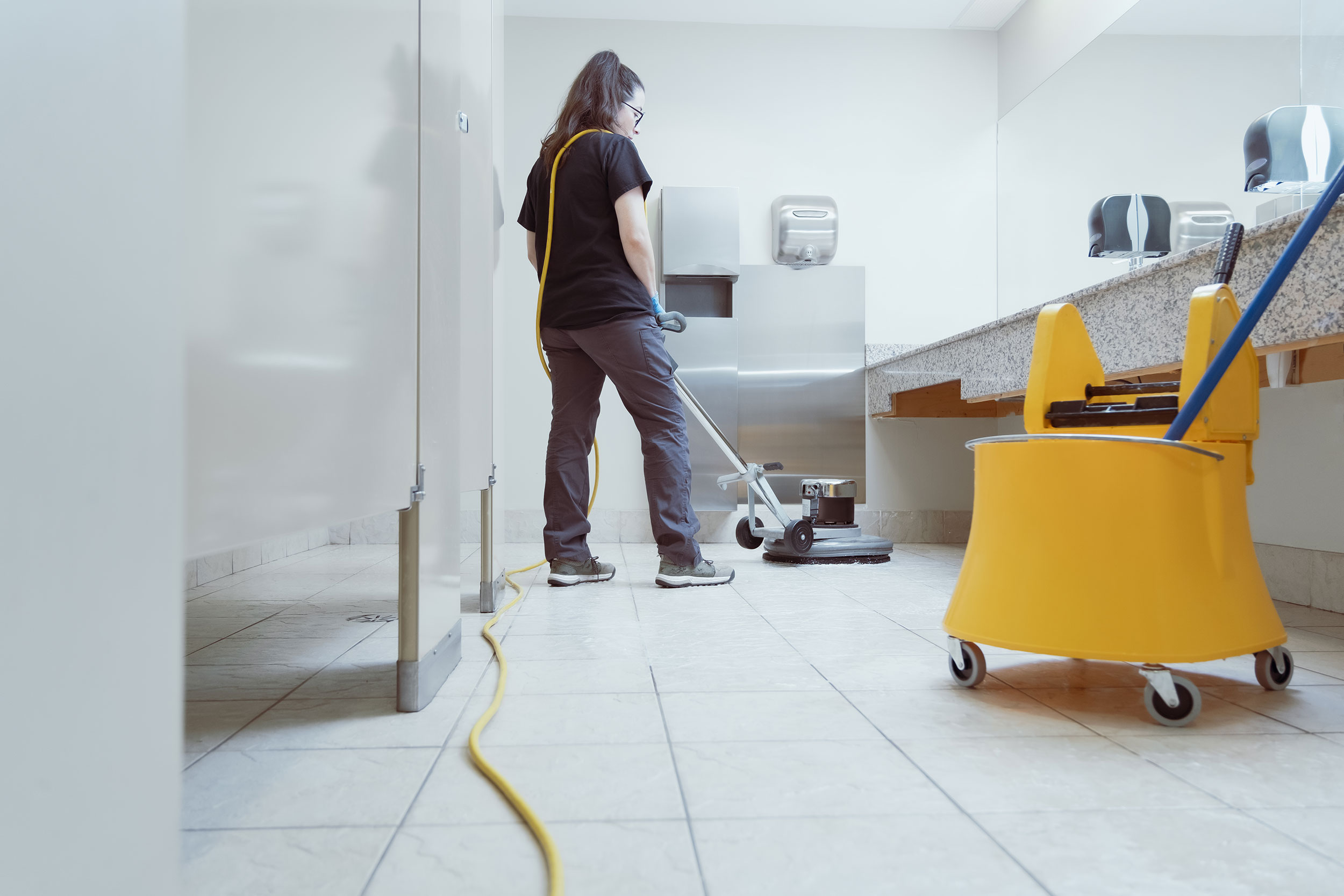 DMC Cleaning scrubbing bathroom floor with industrial machine